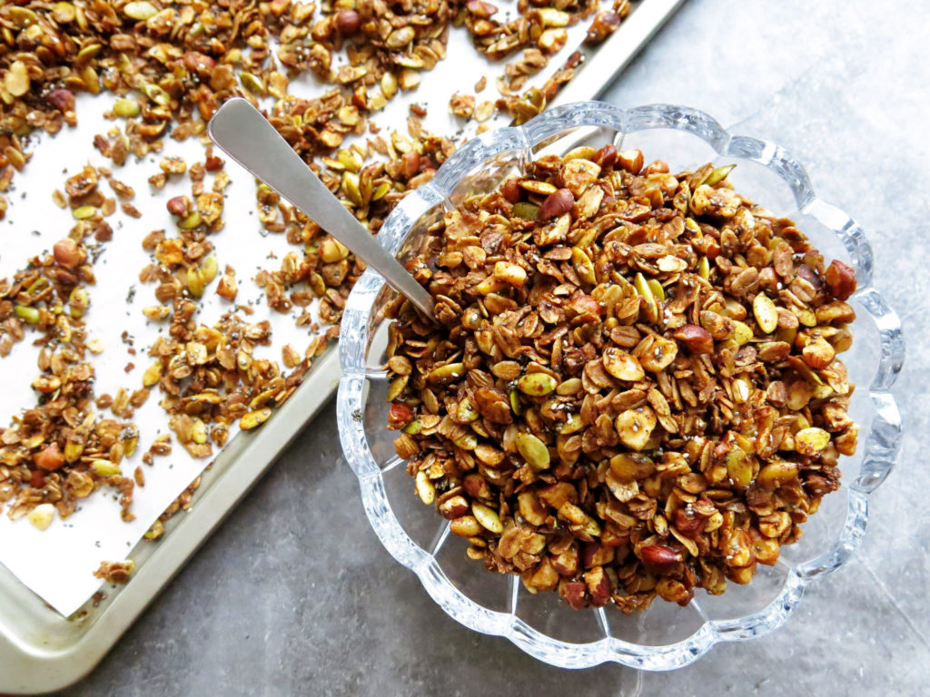 maple spice granola in a bowl with sheet tray in the background