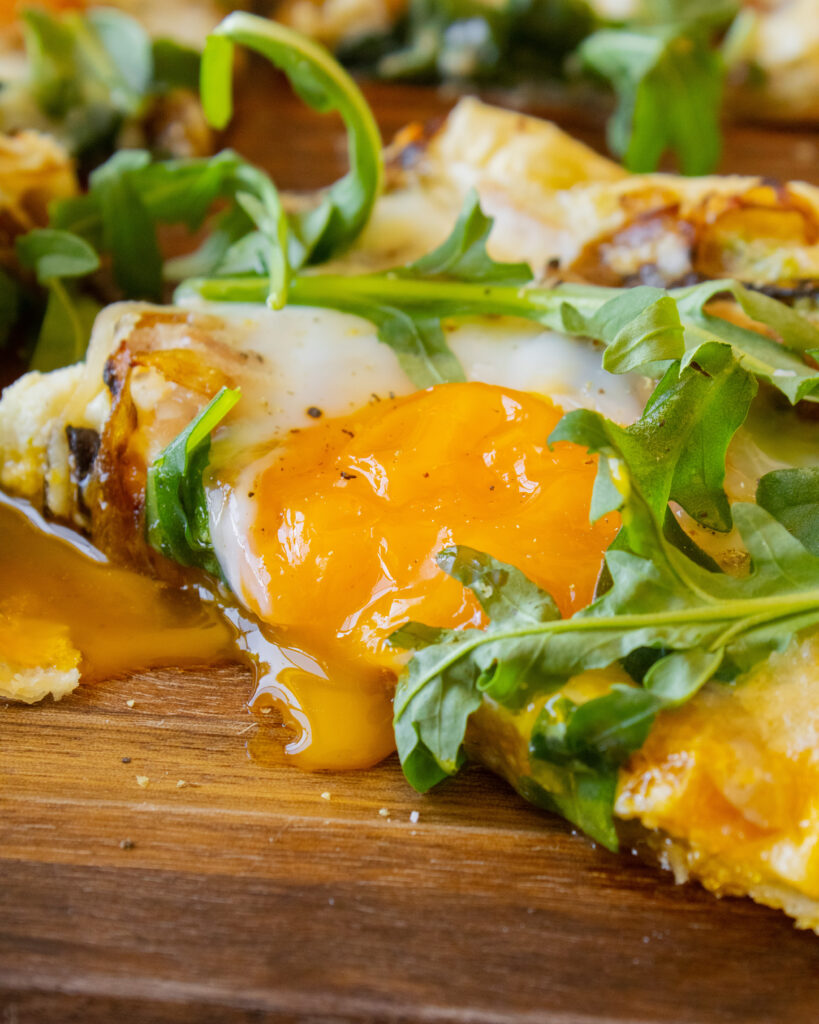 close up of runny egg yolk on a slice of Breakfast Puff Pastry Tart