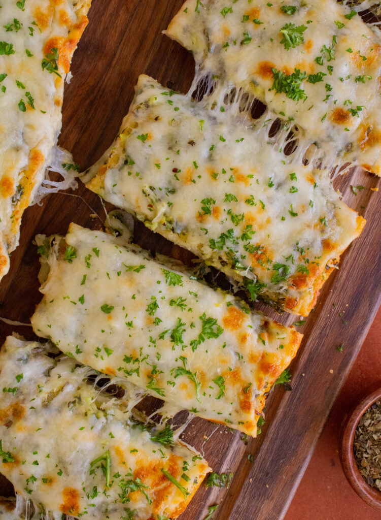 overhead close up  shot of Cheesy Garlic Bread slices with cheese pulls