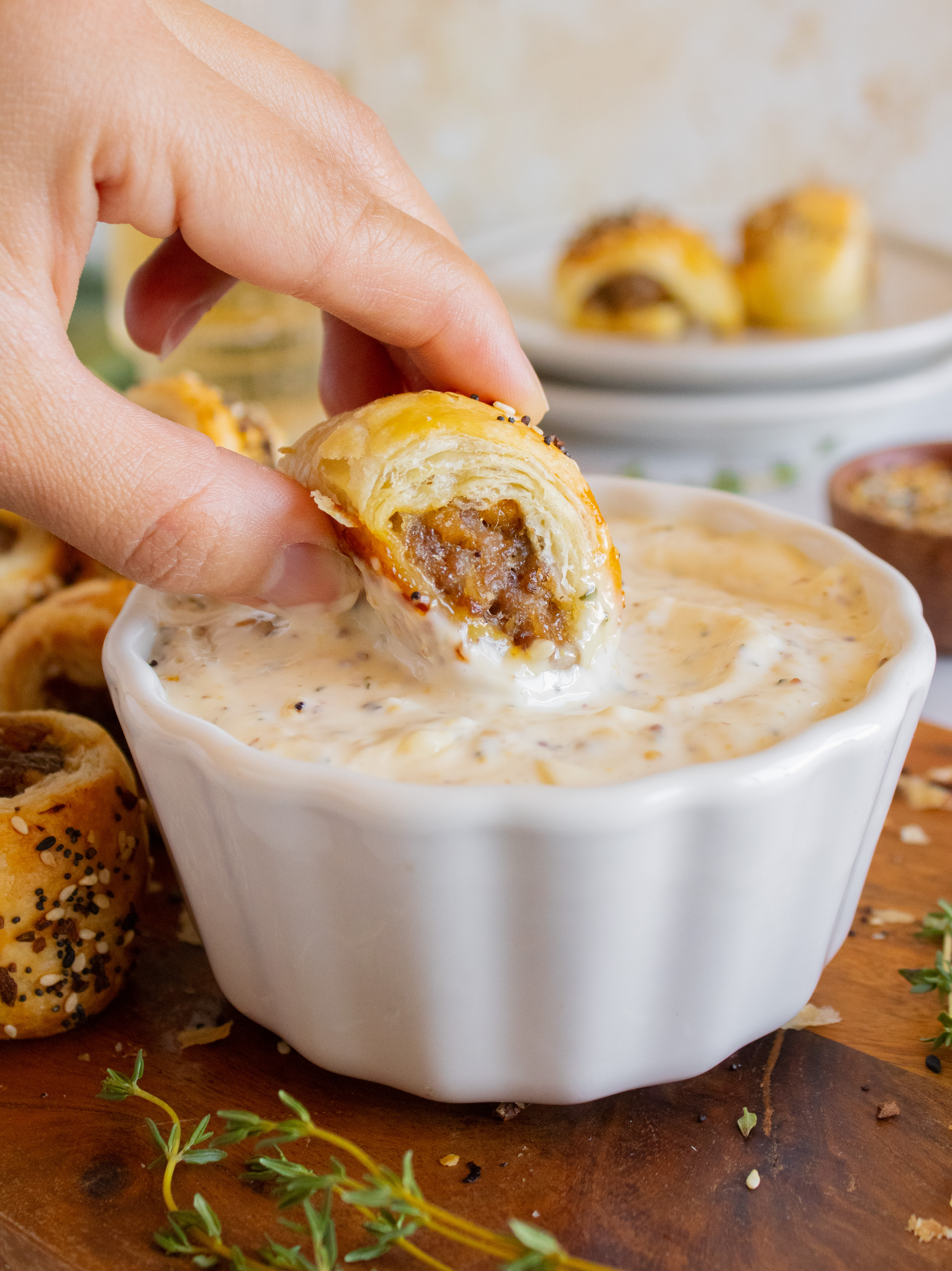 Close up of dipping Sweet Apple Sausage Rolls into garlic mustard sauce