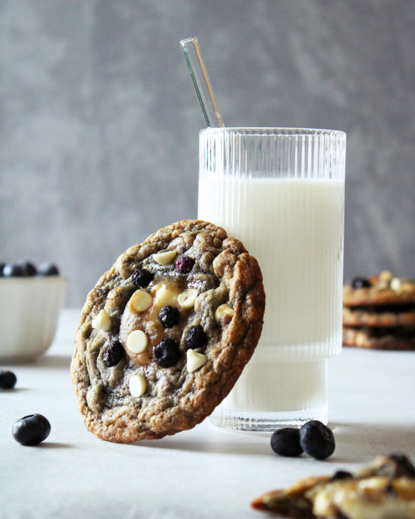 Blueberries and Cream Cookie leaning against glass of milk