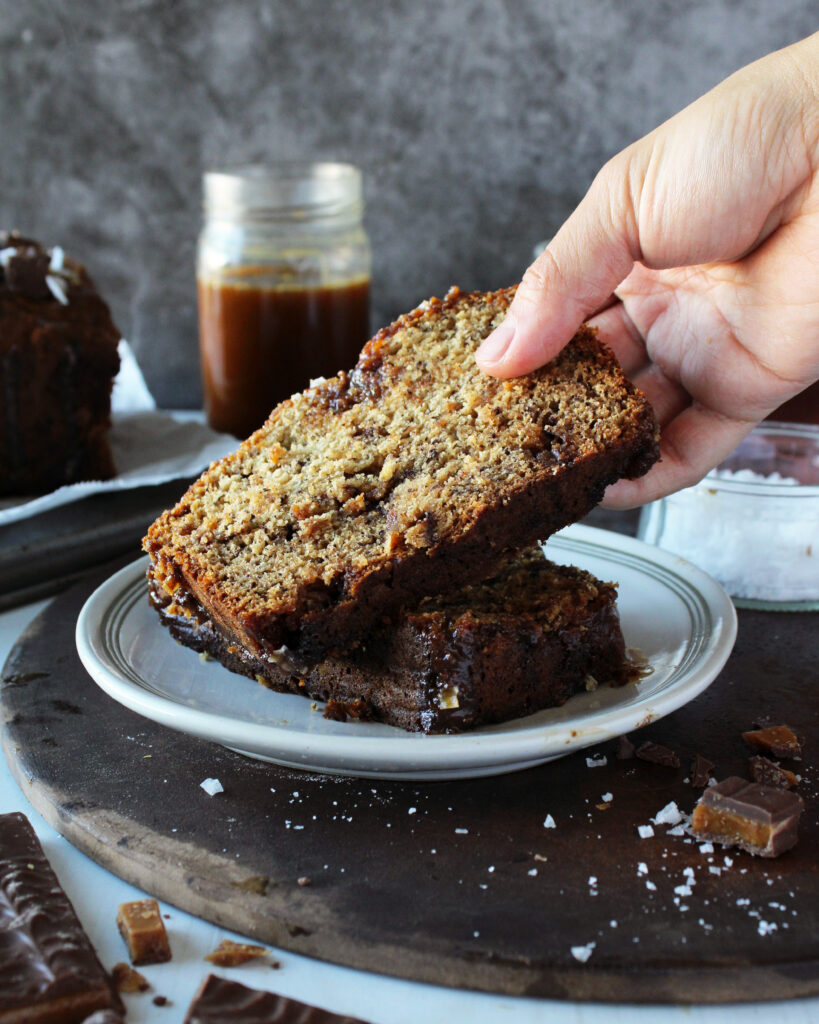 Hand taking a slice of Salted Caramel Toffee Banana Bread 