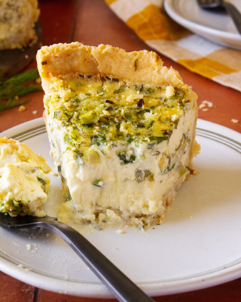 straight on shot of a bite taken out of spring onion quiche