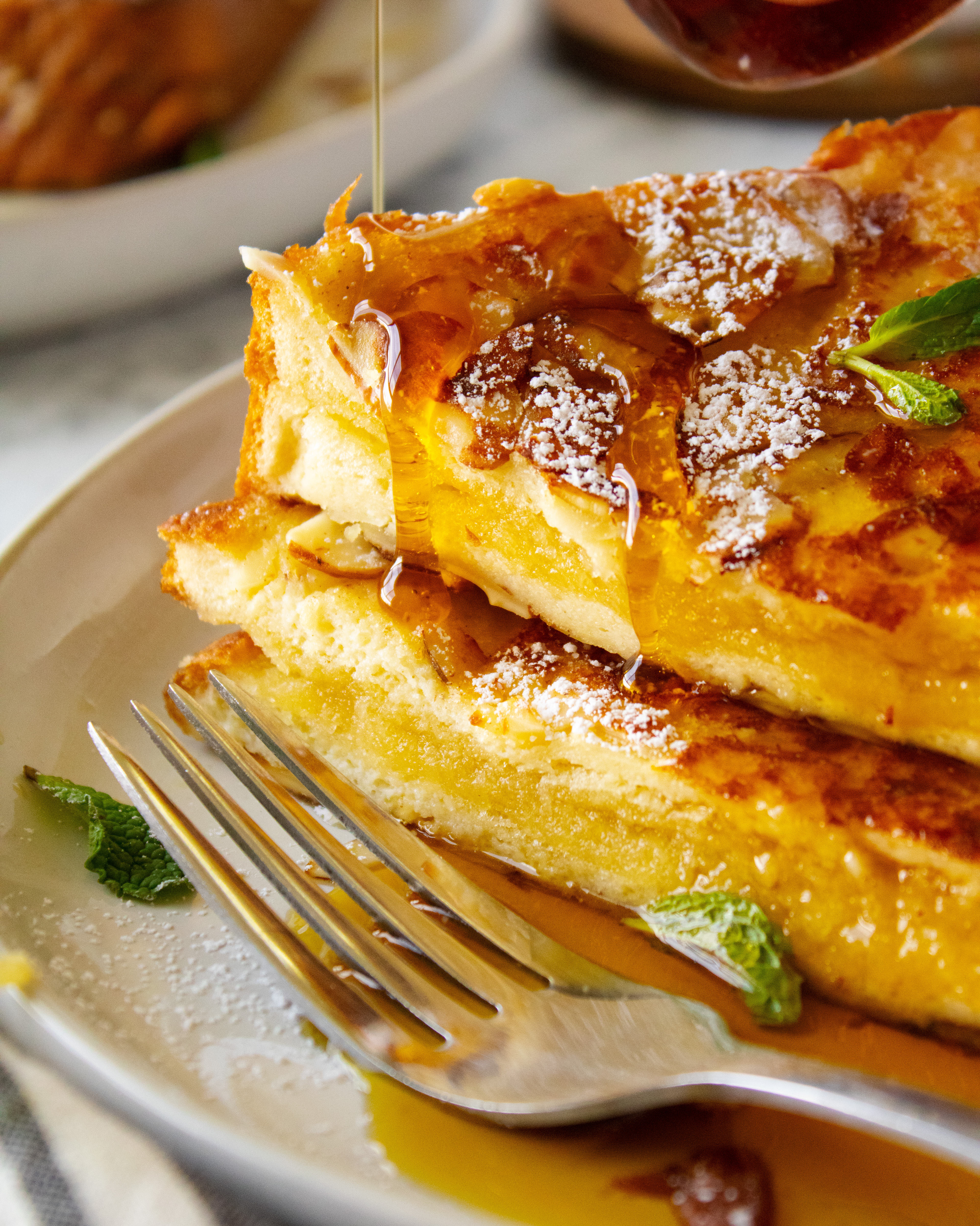close up of maple syrup drizzling onto Almond Croissant French Toast