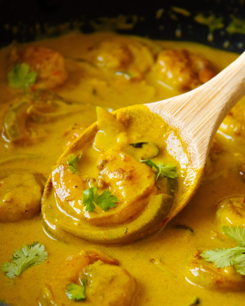 Close up of a Creamy Turmeric Shrimp Curry on a wooden spoon