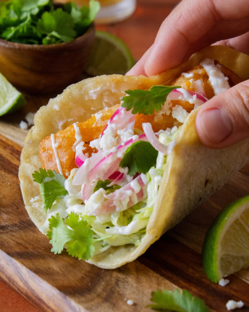 folding a beer battered fish taco in hand