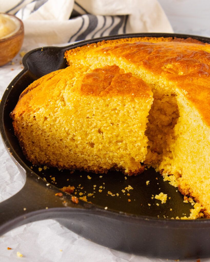 slice of Honey Butter Cornbread in the cat iron skillet