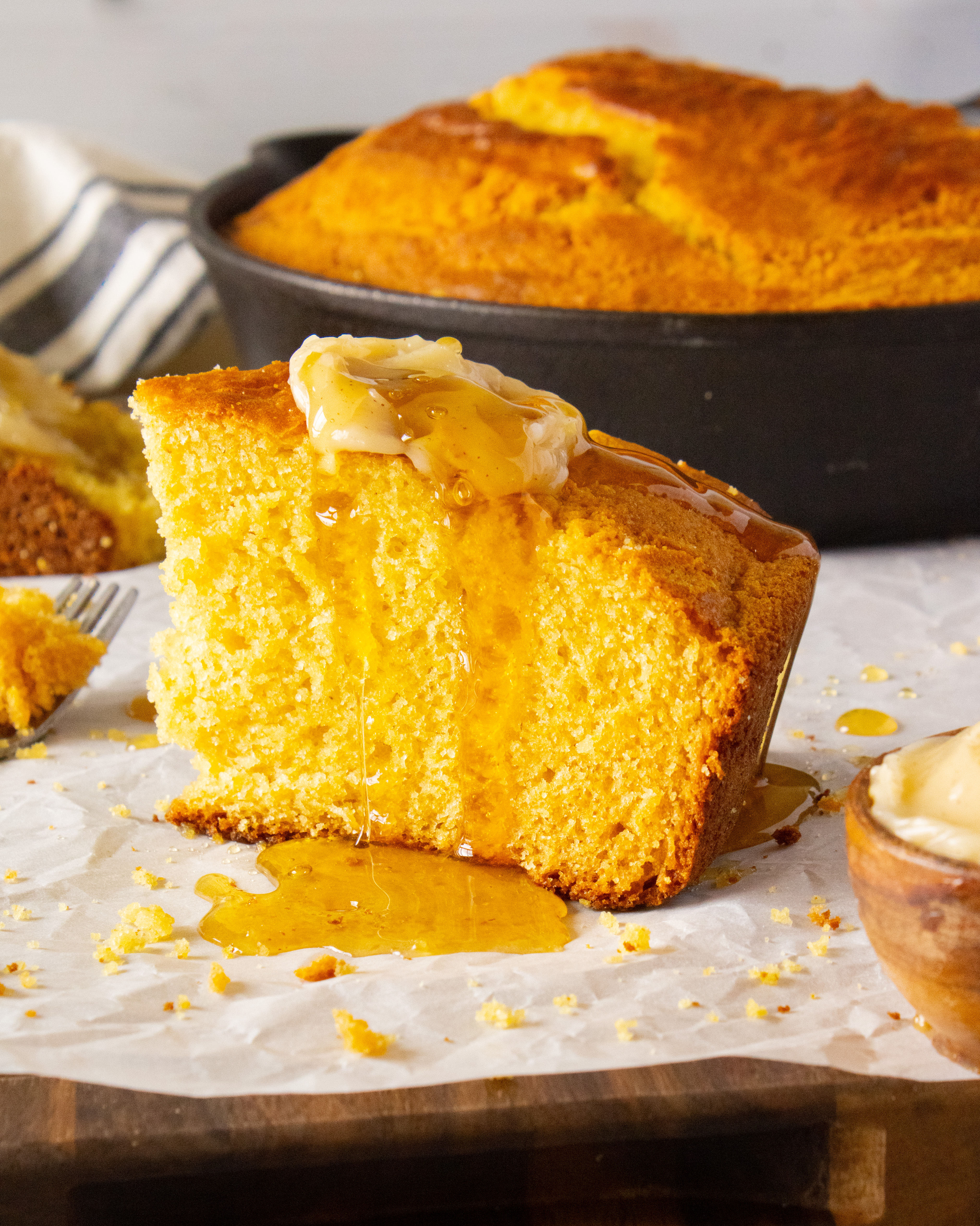standing slice of Honey Butter Cornbread with honey drizzling down the sides