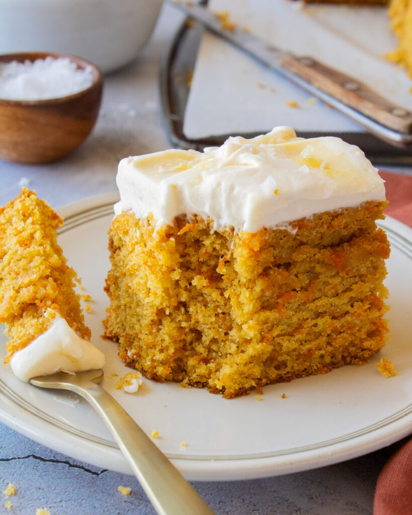 slice of Tahini Carrot Cake with Salted Maple Whipped Cream with a bite taken out