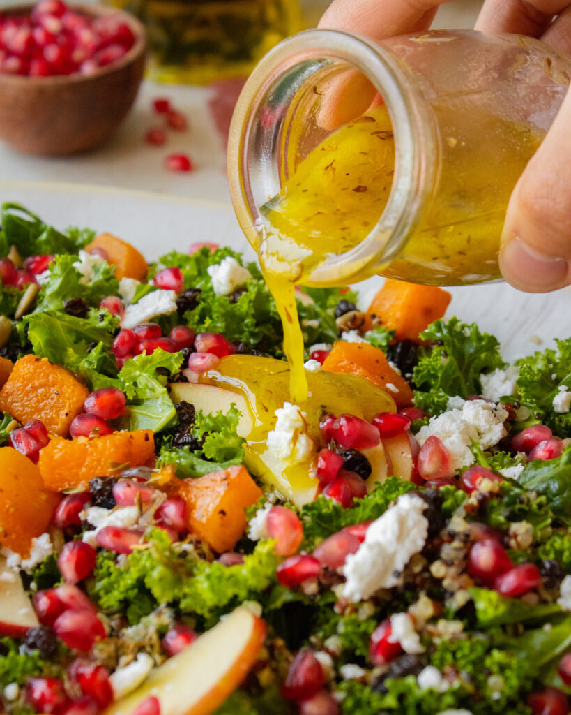 pouring vinaigrette over Fall Harvest Kale Salad