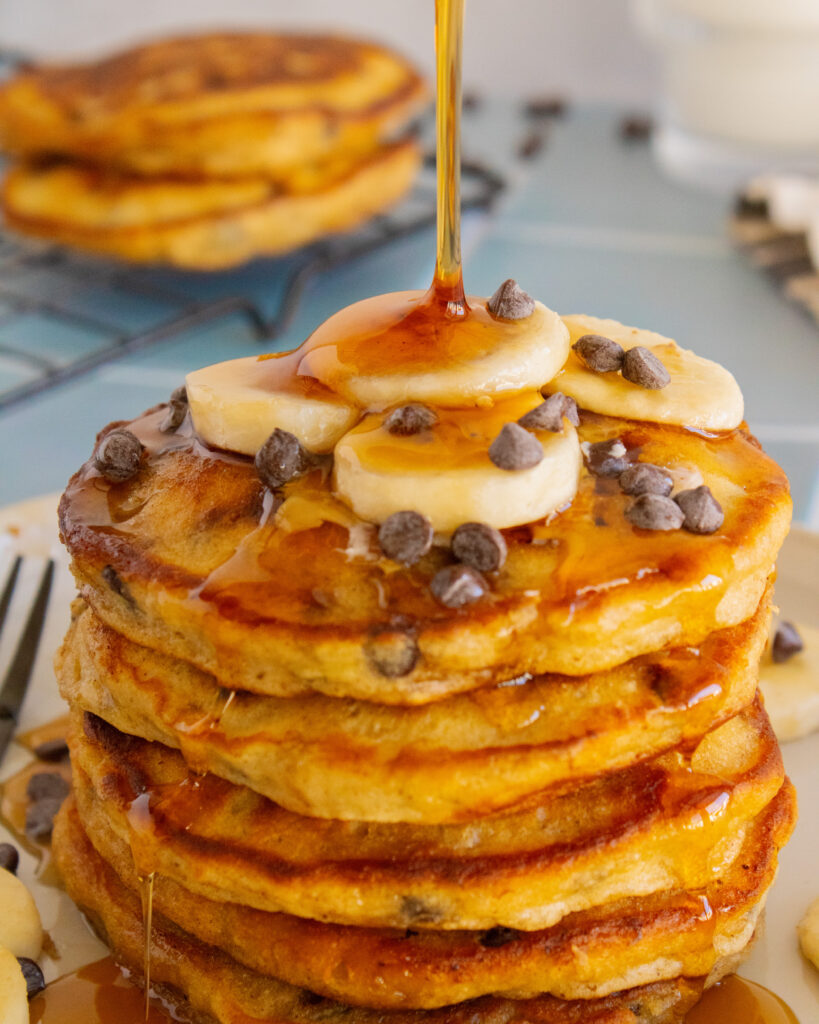 pouring syrup onto Chocolate Almond Banana Pancakes 