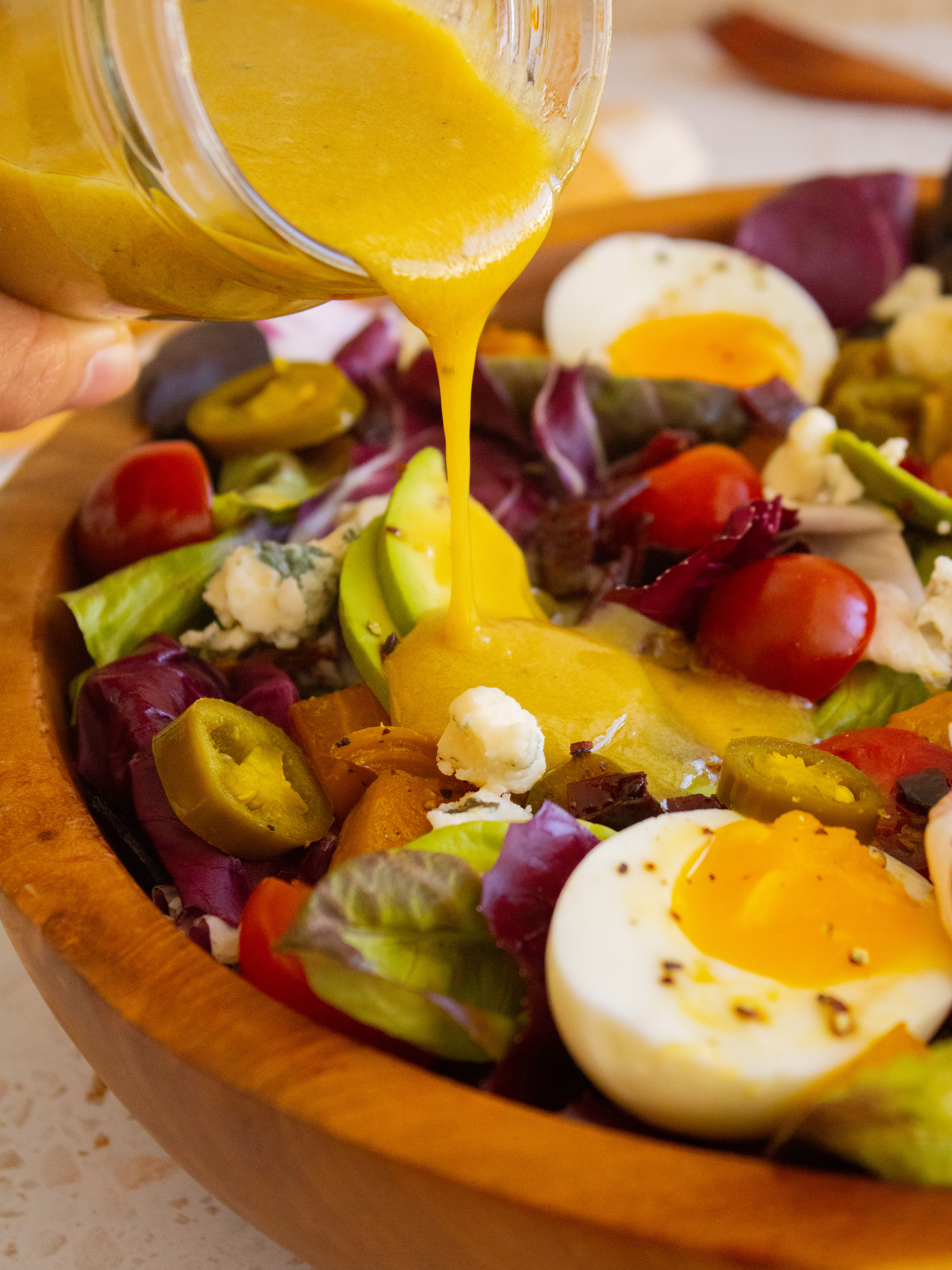 pouring dressing onto Copycat Goop Cobb Salad
