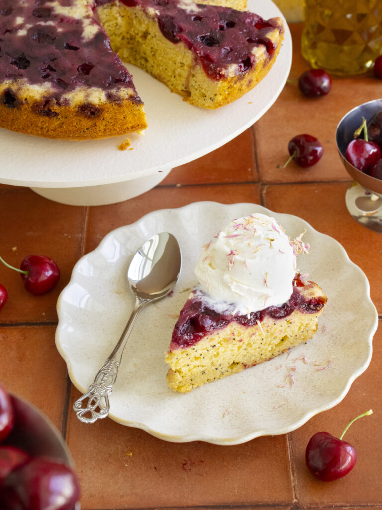 slice of Cherry Olive Oil Cake with full cake in background