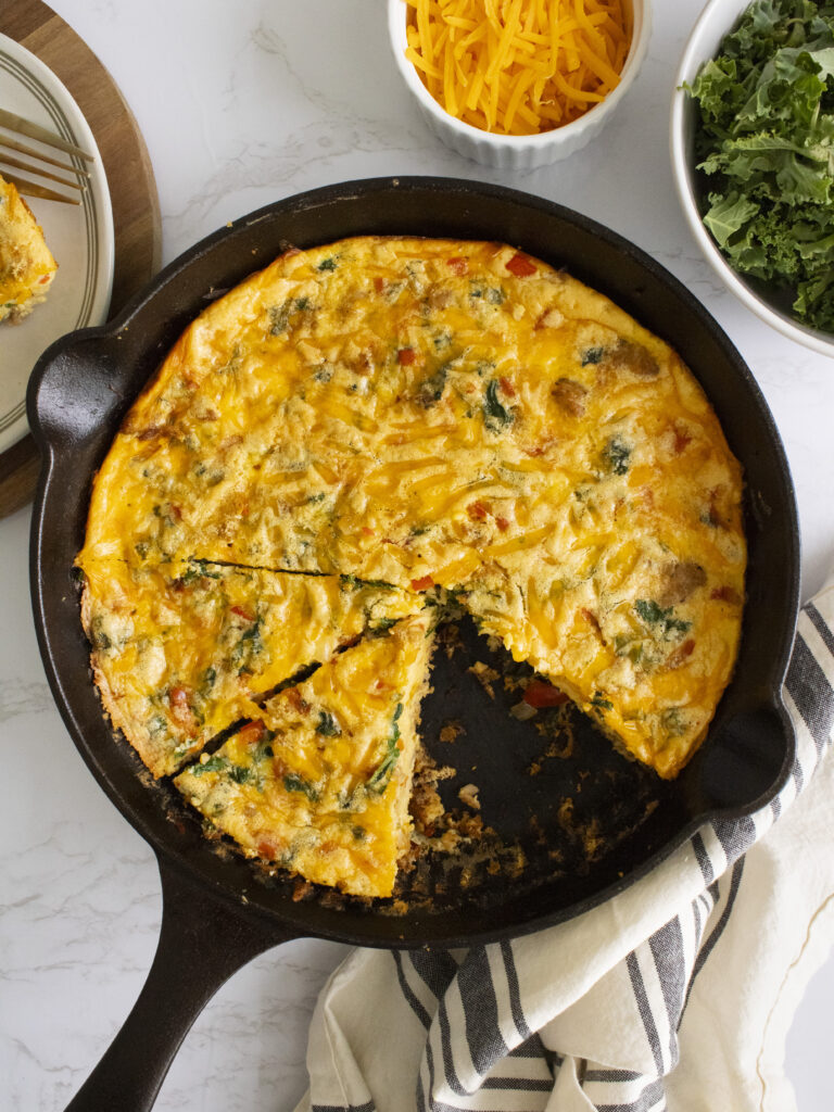 overhead photo of Kale and Sausage Frittata in a cast iron pan with slices cut