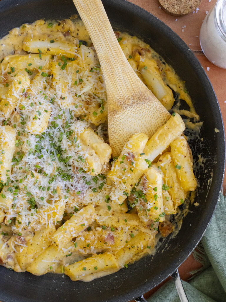 overhead photo of Carbonara Tteokbokki scooped onto a spoon resting in the pan