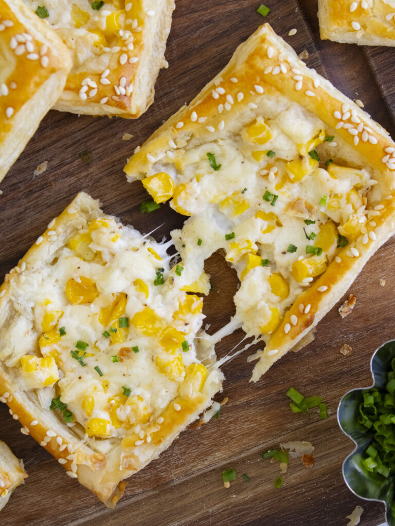 Corn Cheese Puff Pastry Tarts ripped in half with a cheese pull