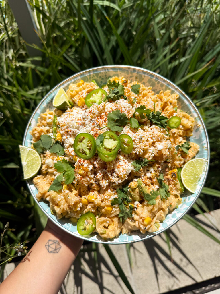 holding a bowl of Elote Pasta Salad in hand