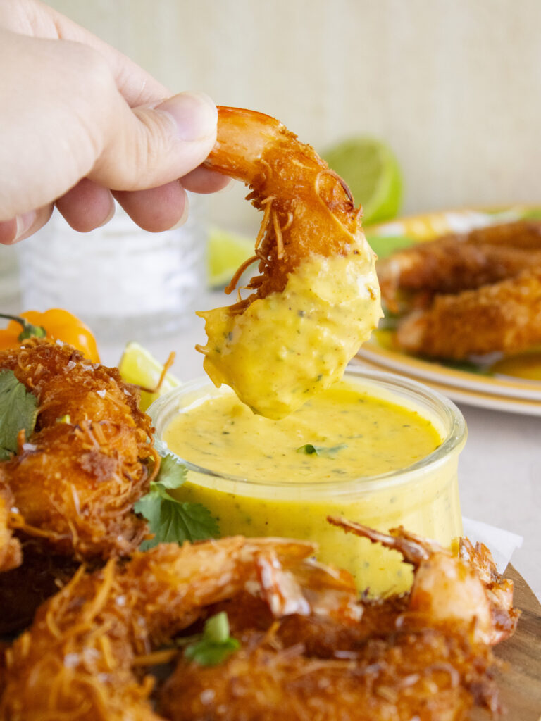 Coconut Shrimp with Mango Habanero Aioli being dipped into sauce